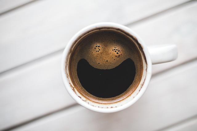 aerial shot of coffee in a coffee mug with bubbles making a smile