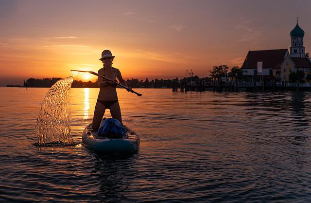 woman on her knees on a paddleboard at sunset